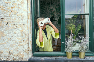 Vrouw kijkt uit raam met wcrollen als verrekijker